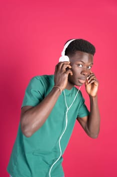 A young man wearing headphones and a green shirt. He is looking at the camera. The image has a bright and energetic mood