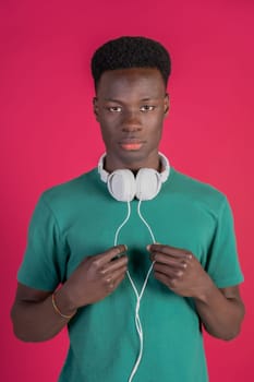 A young man wearing a green shirt and white headphones. He is holding the headphones in his hands