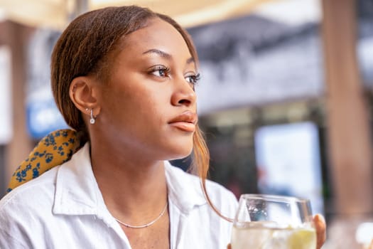 A sophisticated woman is sitting at a table in the vibrant city of Bilbao, savoring a glass of wine.