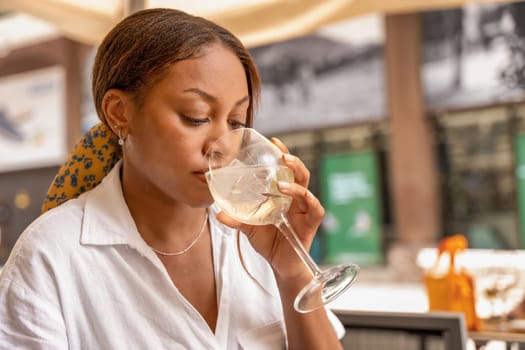 A sophisticated woman sits at a table, gracefully holding a glass of wine in the vibrant city of Bilbao.