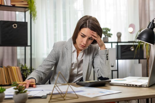 Depressed desperate businesswoman feeling worried about financial problem doing paperwork. Stressed freelancer looking frustrated thinking of money debt, budget loss, bankruptcy at home office desk.