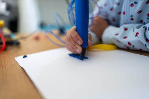 3D pen Close-up of girl creating plastic 3D model, drawing. Unknown child's hand draws with pen on paper at table. Technology. Robotics. STEAM education. Modern technologies.