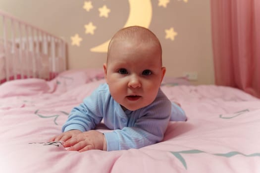 Peaceful baby lays on a bed next to a crib, surrounded by a cozy atmosphere and gentle tones.