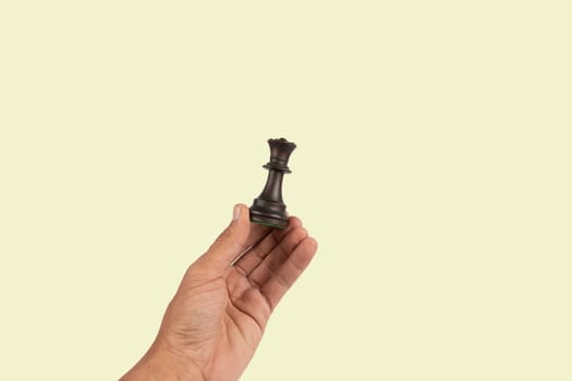 Black male hand holding a black queen chess figure isolated on green background. High quality photo