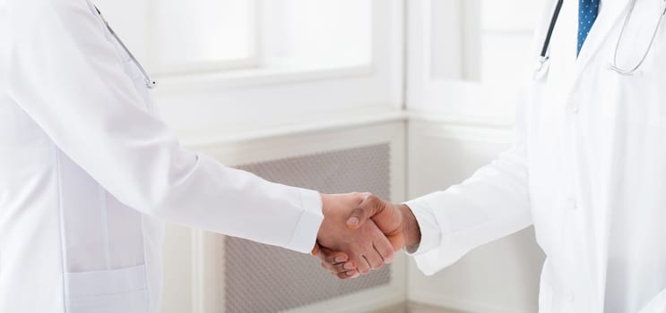 Deal! Concept of collaboration in medicine. Doctors shaking hands in clinic