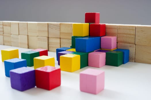 Allyship and teamwork concept. Colored wooden cubes overcome the obstacle.