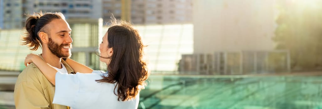Cheerful young caucasian guy in casual meets woman, hugs at train station or airport, outdoor. Date, love, relationship and travel lifestyle, romance trip, summer vacation together, copy space