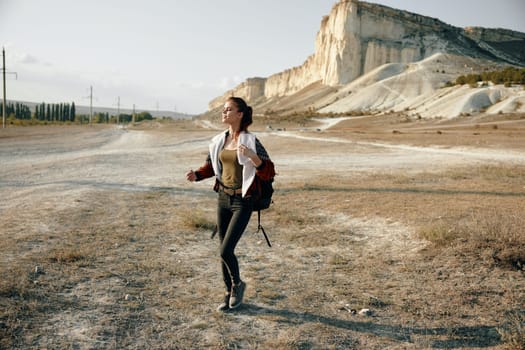 Wandering in the desert a woman hikes with a backpack under a clear blue sky and towering mountain