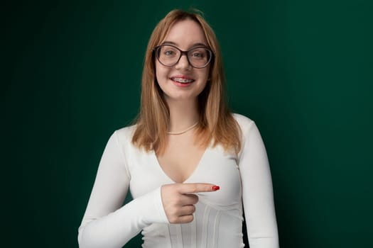 A woman with glasses pointing at an object in the distance. She is focused and appears to be directing attention towards a specific thing with her hand. The womans facial expression conveys determination and focus.