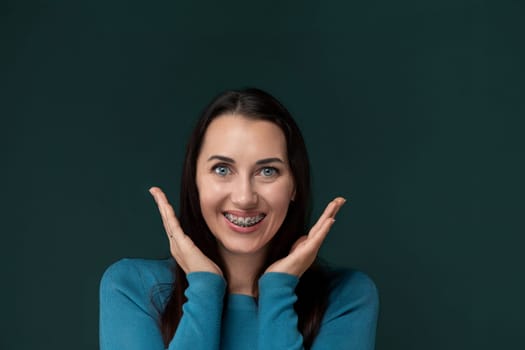 A woman is seen in the image, pulling a funny face while using her hands to distort her features. Her expression is playful and exaggerated, creating a humorous moment captured in the photograph.