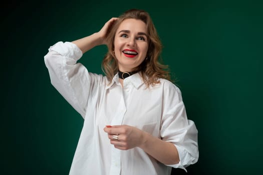 A woman wearing a white shirt is standing and striking a pose for a photograph. She looks directly at the camera with a confident expression, showcasing her outfit and style.