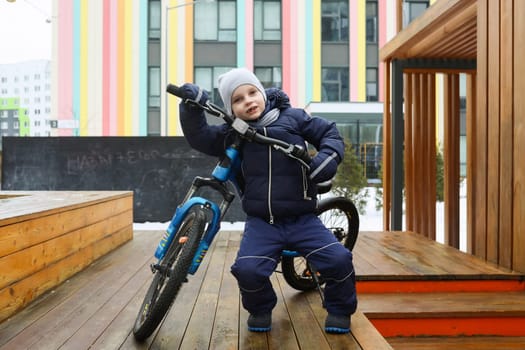 A little boy in a snowsuit went out for a bike ride.