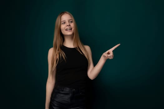 A woman in a black top is pointing at an unknown object or direction with a serious expression on her face. Her finger is extended, indicating a point of interest or concern.