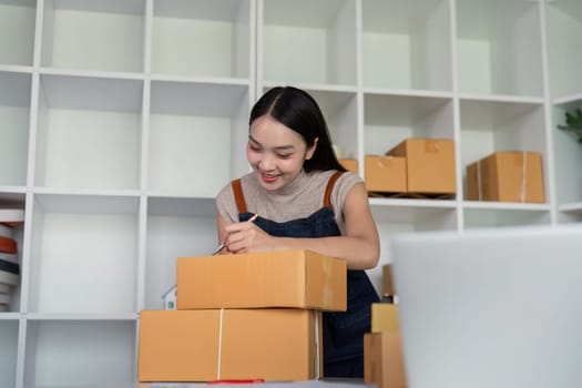 A young entrepreneur prepares parcel boxes for delivery in a modern workspace, showcasing the process of online ecommerce business and product shipping.