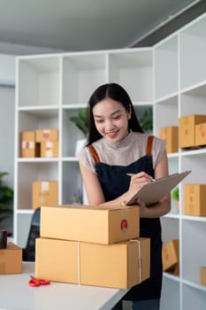 A young woman prepares and organizes parcel boxes for delivery in an online ecommerce business, showcasing the process of modern online selling and product dispatch.