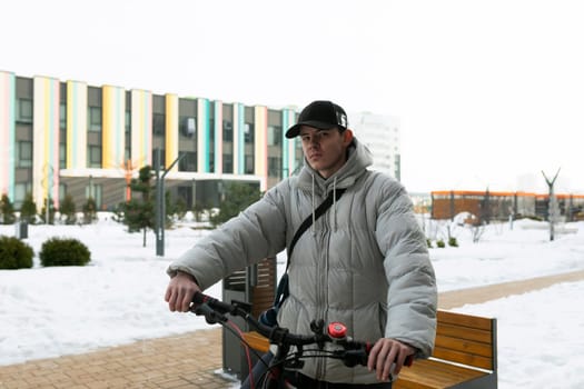 A man in a cap stands with a bicycle in the courtyard of a house.