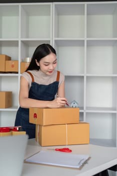 A young woman prepares parcel boxes for delivery in a modern office, representing the process of online ecommerce business and product shipping.