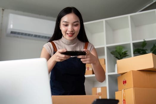 A young woman prepares parcel boxes and takes product photos for her e-commerce business, showcasing the process of online selling and product delivery.