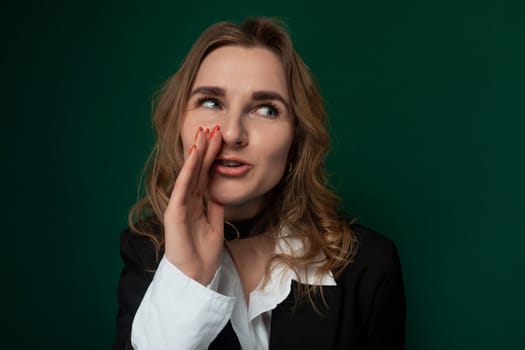 A woman stands with a surprised expression on her face, her eyes widened and mouth slightly open. She appears shocked or astonished by something she has just seen or heard.