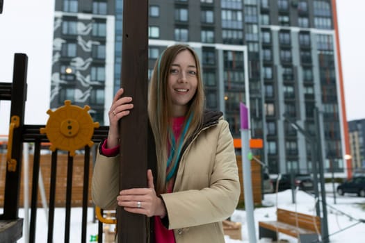 A woman standing alone next to a metal pole in a snowy landscape. She is dressed warmly and appears to be observing her surroundings.