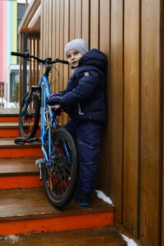 Child boy took a bike for a walk in winter.