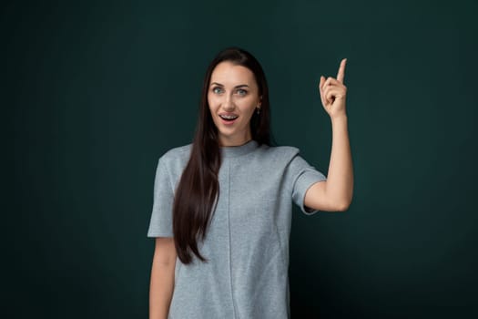 A woman is pointing at an object or direction with her finger, indicating something of interest. She is likely drawing attention to a specific item or location.