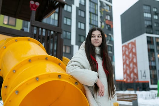 A woman is standing beside a massive yellow structure, looking up at it with a curious expression. The object seems to dominate the scene, showcasing its size and vibrant color.