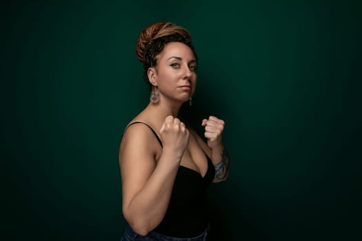 A woman in a black top confidently strikes a pose while someone takes her picture. Her posture exudes self-assurance, and she looks directly at the camera with a subtle smile.