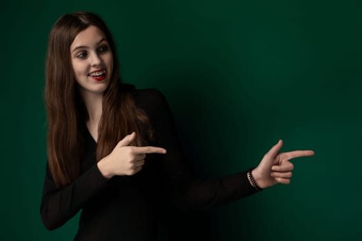 A woman with flowing long hair extends her arm and points at an unseen object with a focused expression. Her gesture appears confident and purposeful, drawing attention to whatever has caught her eye.