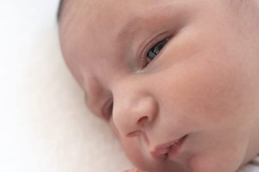 Closeup of a newborn baby's hface on white blanket. High quality photo