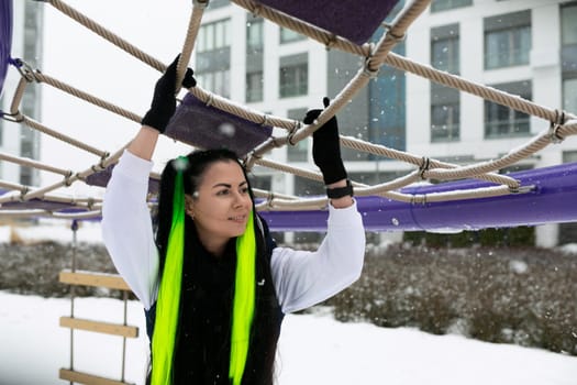A woman is seen tightly gripping onto a rope in a snowy environment. She is shown bracing against the elements, displaying strength and determination in the face of challenging conditions.