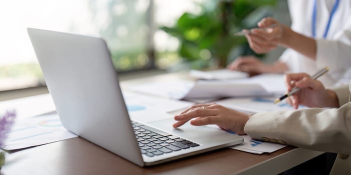 Team members collaborating on business planning and analysis, using a laptop and documents in a modern office environment.