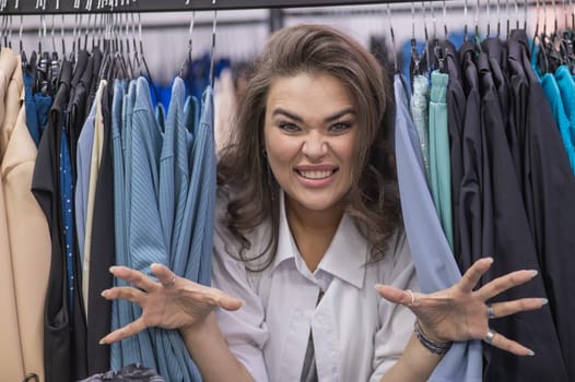 A fat woman in a plus size store peeks out from behind racks of clothes