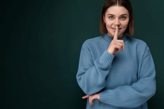 A woman wearing a blue sweater is pulling a funny face, causing her features to contort in a humorous expression. Her eyes are wide, and her mouth is twisted into a comical shape, creating a playful and lighthearted moment.