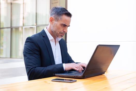 Business on the move: Businessman working on his laptop on the street. Man Hands Type On His Laptop Outdoors