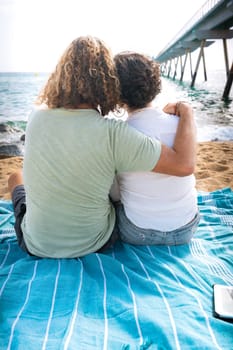 Smiling couple wearing sunglasses enjoying a vacation embracing looking at the sea.