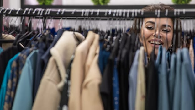 Portrait of a fat woman in a plus size store through hangers with clothes