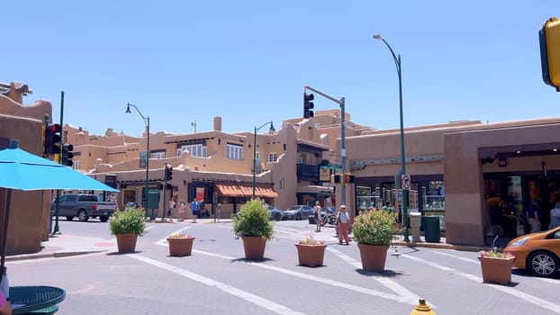 Santa Fe, New Mexico, USA-June 11, 2024-Slow motion-The main square of a historic downtown area featuring traditional adobe buildings, lively shops, and pedestrians enjoying a sunny day.