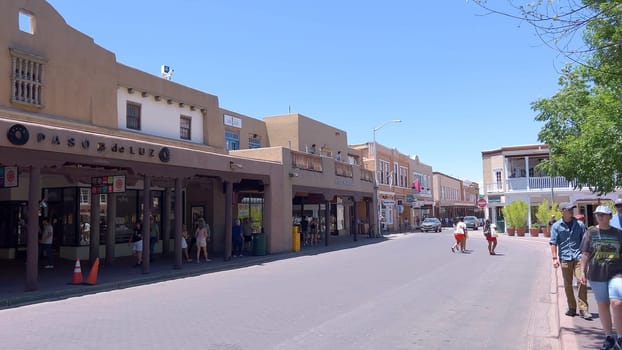 Santa Fe, New Mexico, USA-June 11, 2024-Slow motion-The main square of a historic downtown area featuring traditional adobe buildings, lively shops, and pedestrians enjoying a sunny day.