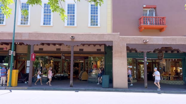 Santa Fe, New Mexico, USA-June 11, 2024-Slow motion-The main square of a historic downtown area featuring traditional adobe buildings, lively shops, and pedestrians enjoying a sunny day.