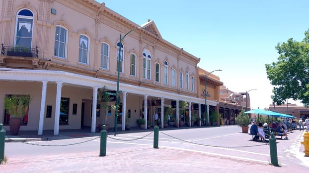 Santa Fe, New Mexico, USA-June 11, 2024-Slow motion-The main square of a historic downtown area featuring traditional adobe buildings, lively shops, and pedestrians enjoying a sunny day.