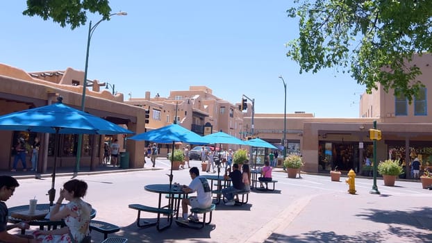 Santa Fe, New Mexico, USA-June 11, 2024-Slow motion-The main square of a historic downtown area featuring traditional adobe buildings, lively shops, and pedestrians enjoying a sunny day.