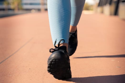 Feet of a sporty woman running through the streets of the city.