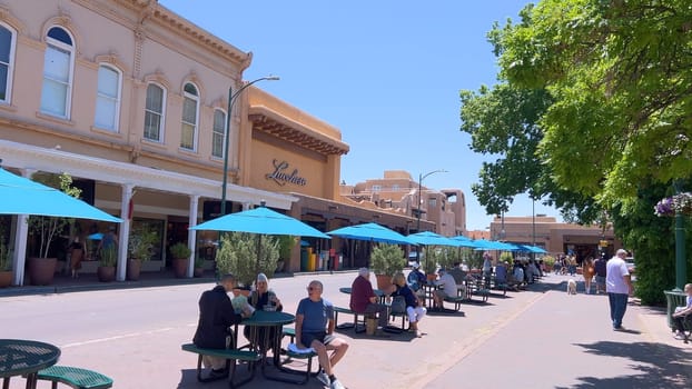 Santa Fe, New Mexico, USA-June 11, 2024-Slow motion-The main square of a historic downtown area featuring traditional adobe buildings, lively shops, and pedestrians enjoying a sunny day.