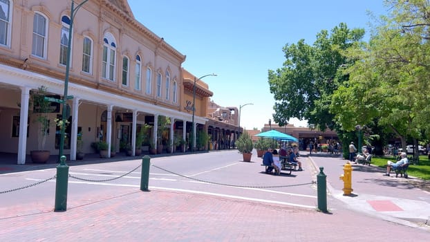 Santa Fe, New Mexico, USA-June 11, 2024-Slow motion-The main square of a historic downtown area featuring traditional adobe buildings, lively shops, and pedestrians enjoying a sunny day.