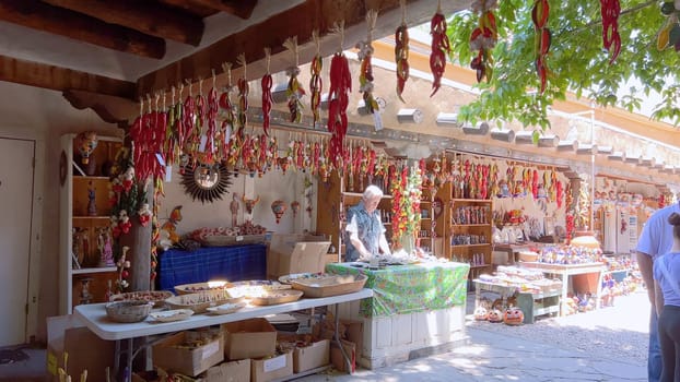 Santa Fe, New Mexico, USA-June 11, 2024-Slow motion-A vibrant outdoor market showcasing an array of colorful ceramics, pottery, and handcrafted items. Shoppers explore the unique local crafts under a sunny sky, surrounded by traditional adobe architecture.