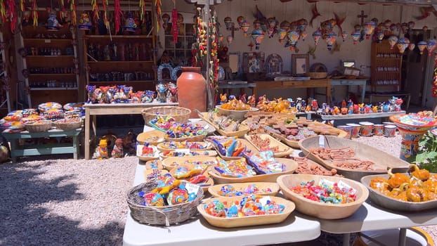 Santa Fe, New Mexico, USA-June 11, 2024-Slow motion-A vibrant outdoor market showcasing an array of colorful ceramics, pottery, and handcrafted items. Shoppers explore the unique local crafts under a sunny sky, surrounded by traditional adobe architecture.