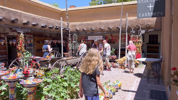 Santa Fe, New Mexico, USA-June 11, 2024-Slow motion-A vibrant outdoor market showcasing an array of colorful ceramics, pottery, and handcrafted items. Shoppers explore the unique local crafts under a sunny sky, surrounded by traditional adobe architecture.
