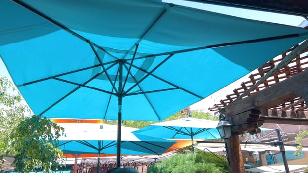 Santa Fe, New Mexico, USA-June 11, 2024-Slow motion-A vibrant outdoor cafe featuring colorful umbrellas providing shade for patrons enjoying their meals on a sunny day. The setting includes lush greenery and a relaxed atmosphere.