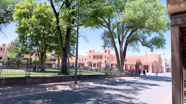 Santa Fe, New Mexico, USA-June 11, 2024-Slow motion-The main square of a historic downtown area featuring traditional adobe buildings, lively shops, and pedestrians enjoying a sunny day.
